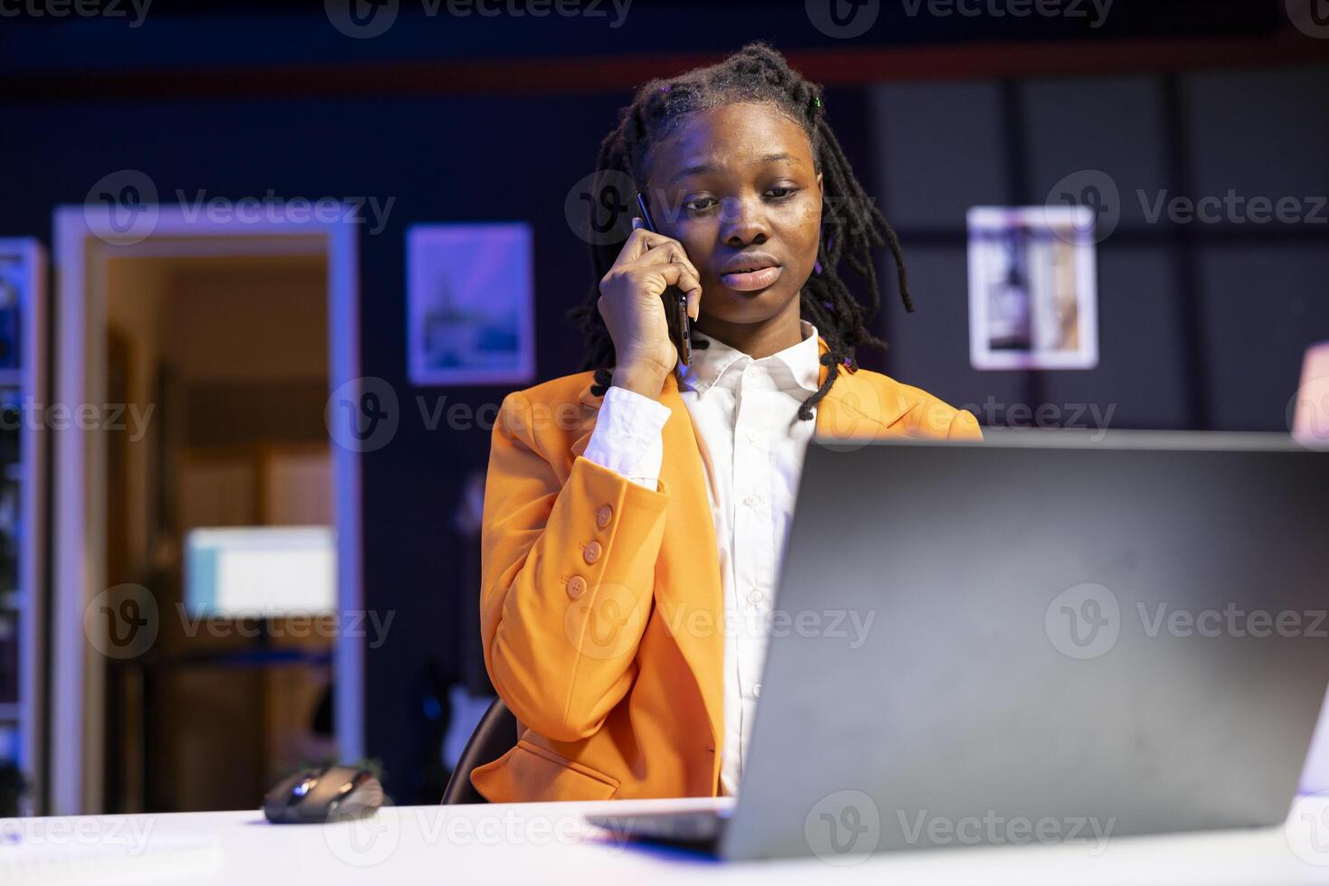 Student at desk in phone call with teacher, requesting help to do homework, browsing internet on laptop. African american person doing telephone call and reading articles on laptop for school tasks photo