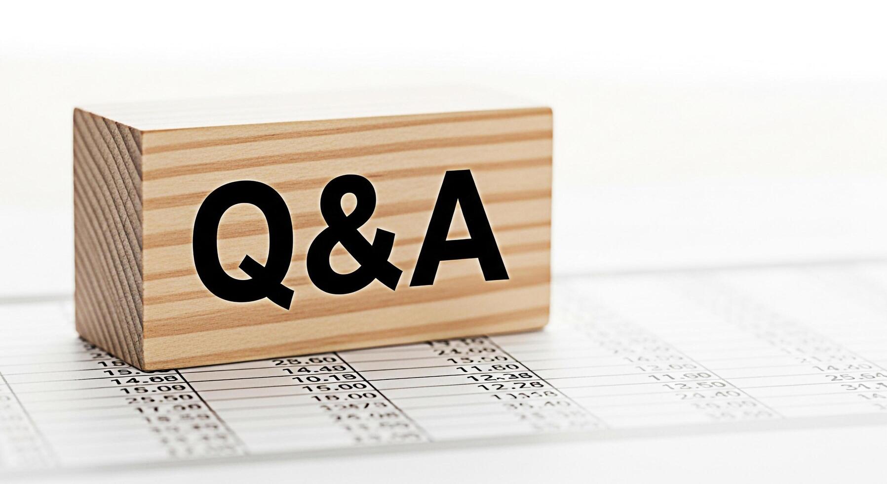 Wooden block displaying QA on a financial document representing questions and answers in a business setting conveying a sense of clarity and information photo