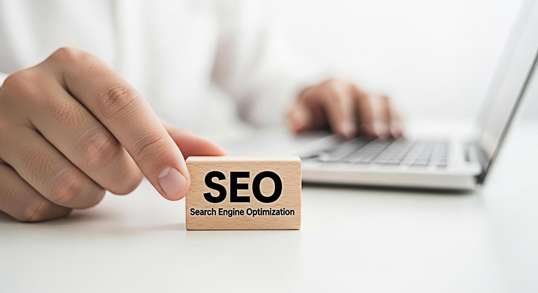 Closeup of a hand placing a wooden block with the word SEO on a white desk while typing on a laptop symbolizing search engine optimization and digital marketing success in a modern office environment photo