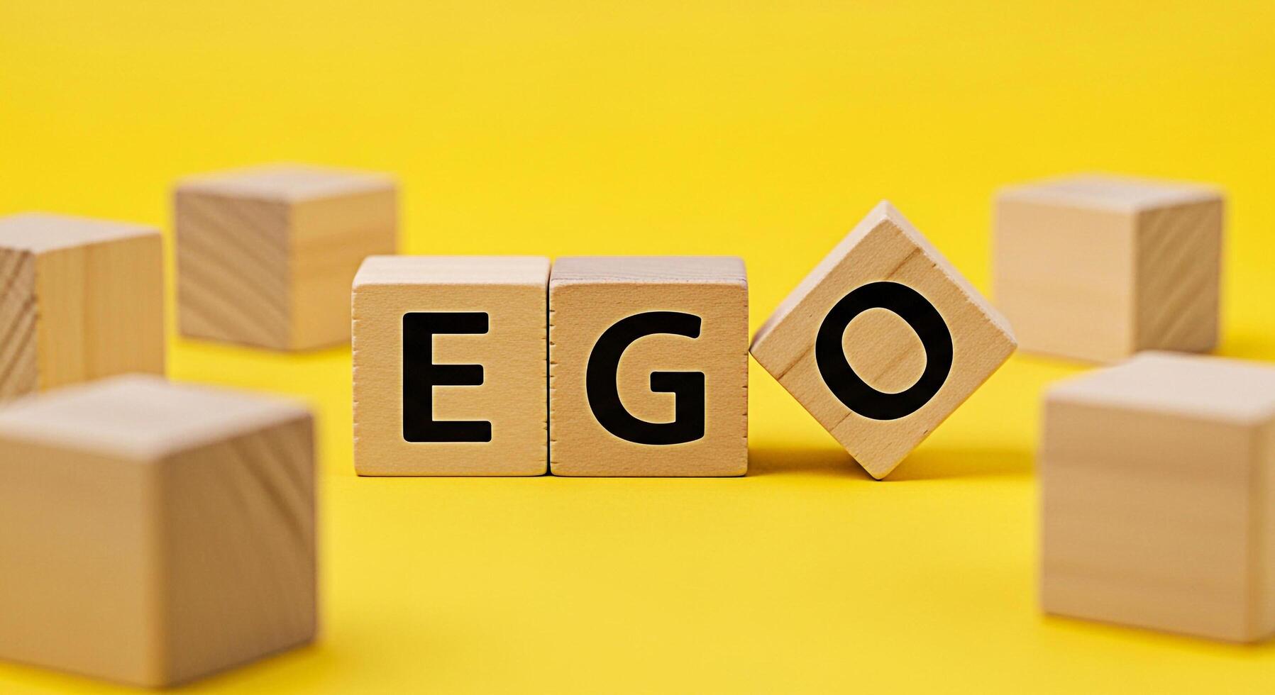 Wooden blocks spelling EGO on a bright yellow background representing selfimportance and inflated selfesteem highlighting the concept of ego and its impact on personal growth and interpersonal relatio photo