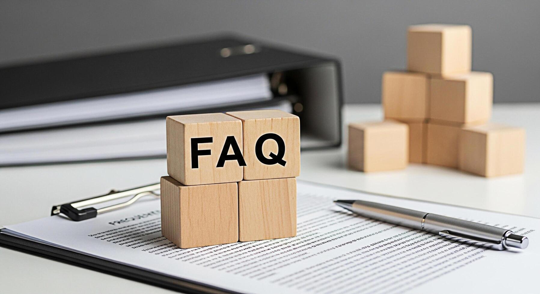 Wooden blocks displaying FAQ on a white desk with a pen and documents representing frequently asked questions and information in a professional setting offering clarity and guidance photo