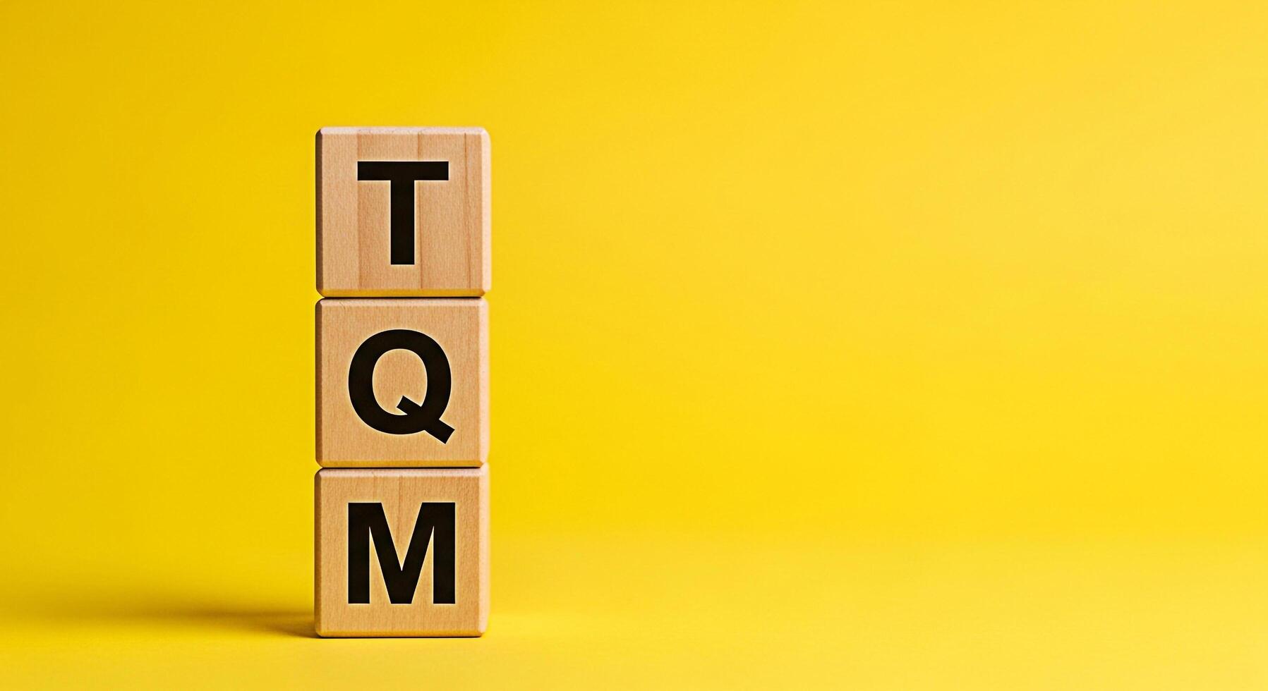 Wooden blocks displaying the letters TQM stacked against a vibrant yellow background symbolizing total quality management and a commitment to excellence in business operations and continuous improveme photo