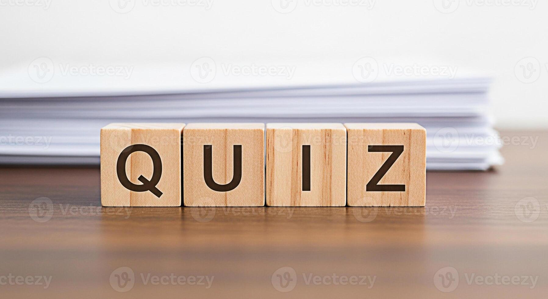 Wooden blocks spelling QUIZ on a wooden table with a stack of papers in the background representing knowledge testing and assessment in an educational setting conveying a sense of challenge and learni photo