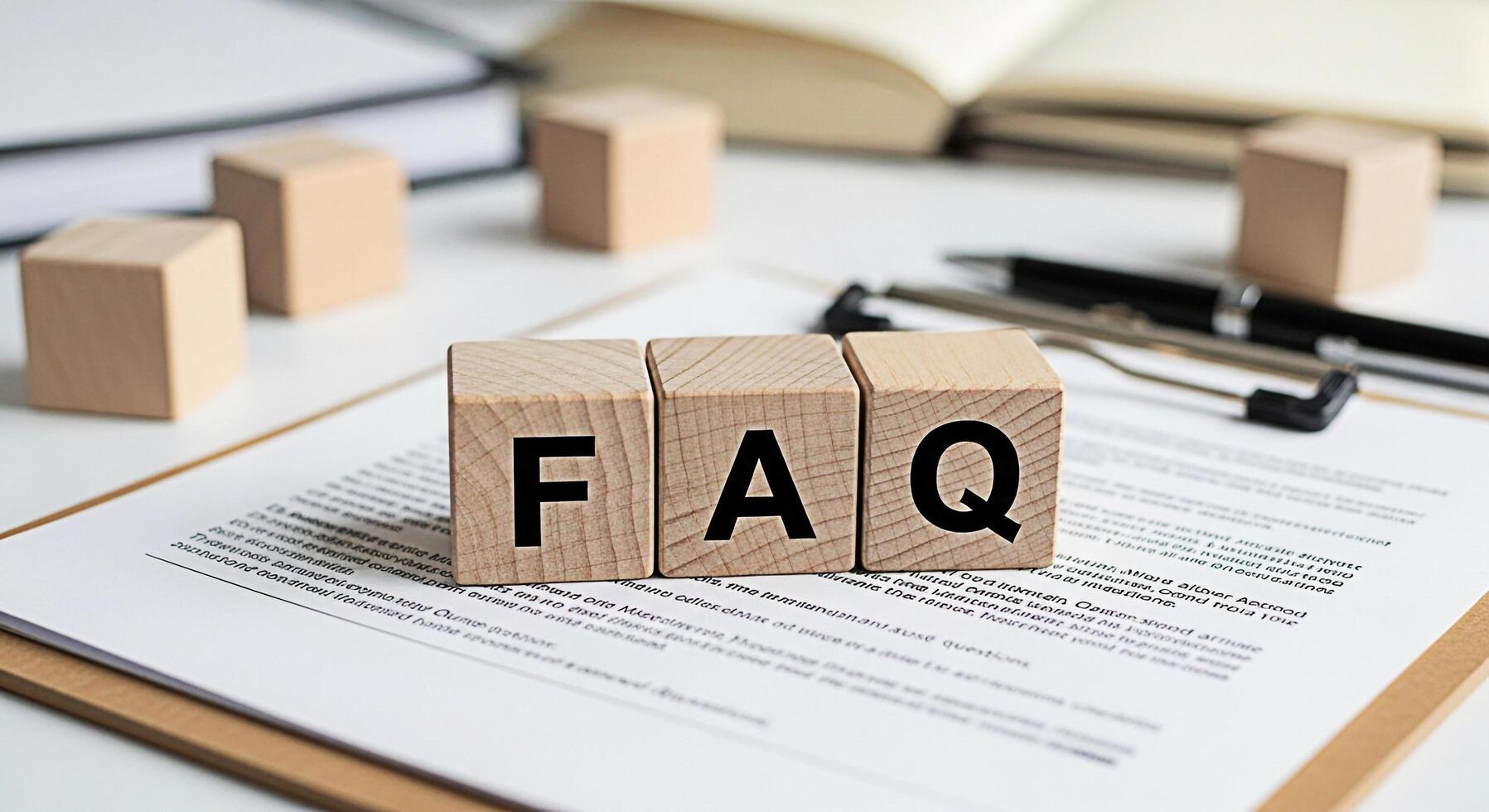 Wooden blocks spelling FAQ on a clipboard with a pen and books in a bright office setting representing frequently asked questions knowledge base customer support and information resources photo