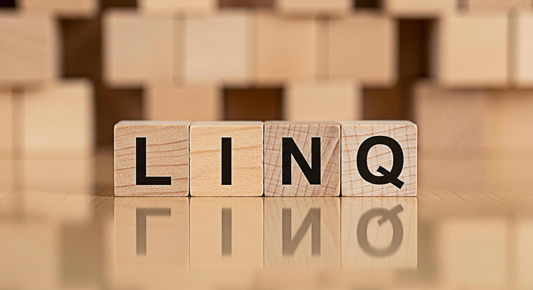 Wooden blocks spelling LINQ on a reflective surface conveying a sense of connection and organization in a bright minimalist setting ideal for illustrating data management and software development conc photo