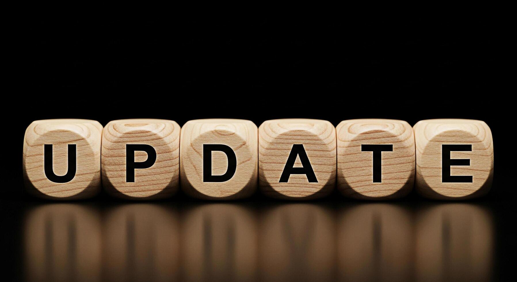 Wooden blocks spelling UPDATE on a reflective surface against a dark background symbolizing software updates system upgrades and the importance of staying current in a technological environment photo