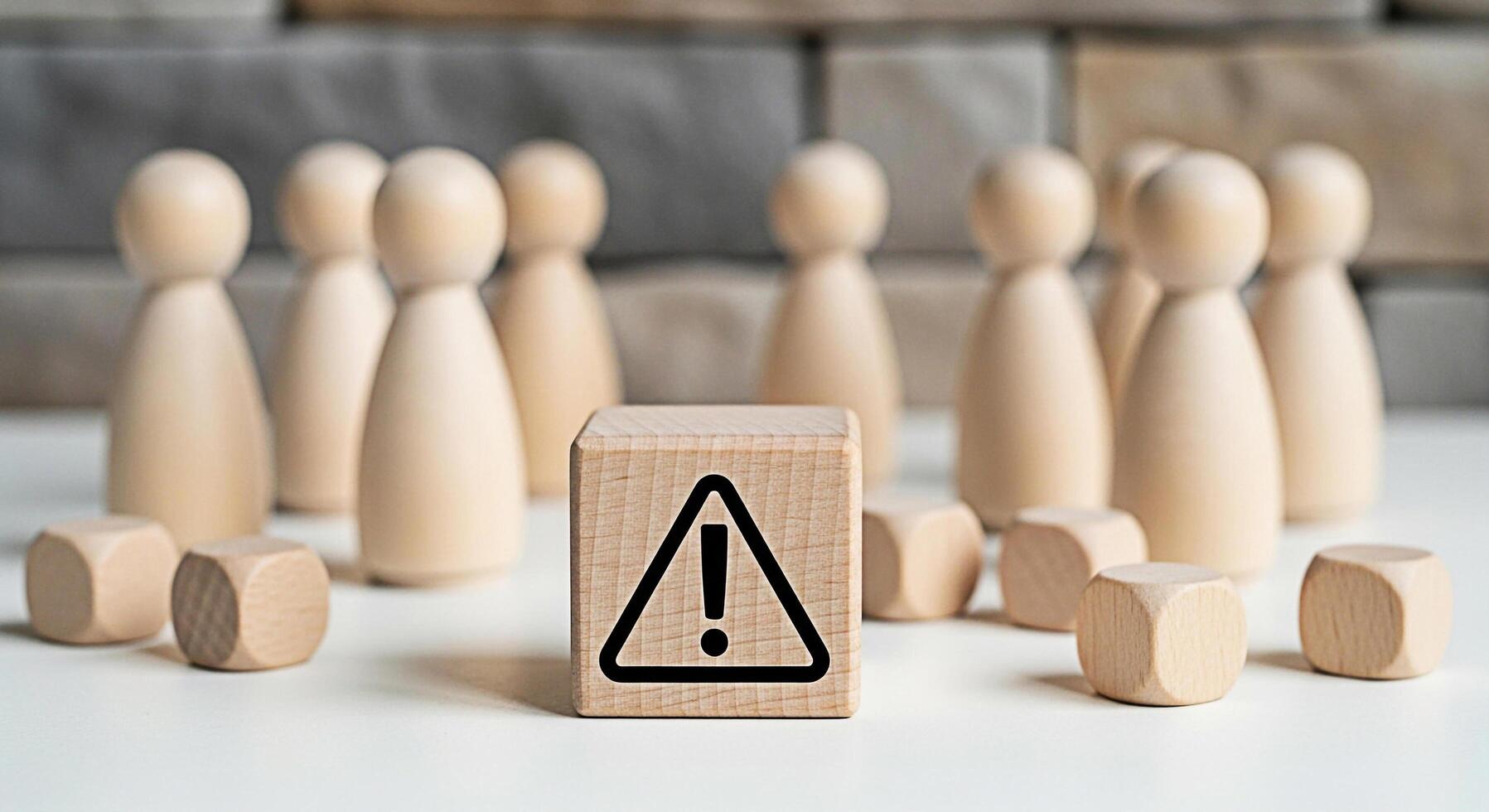 Wooden figures standing behind a warning sign on a table representing a potential risk or danger to a group creating a sense of caution and awareness in a minimalist setting photo