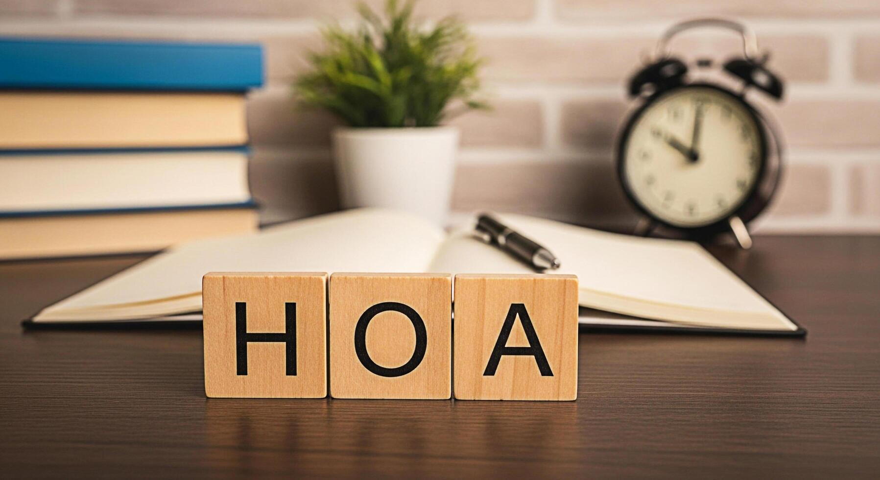 Wooden blocks spelling HOA on a desk with an open notebook and pen symbolizing homeowners association matters in a home office setting creating a sense of organization and community governance photo