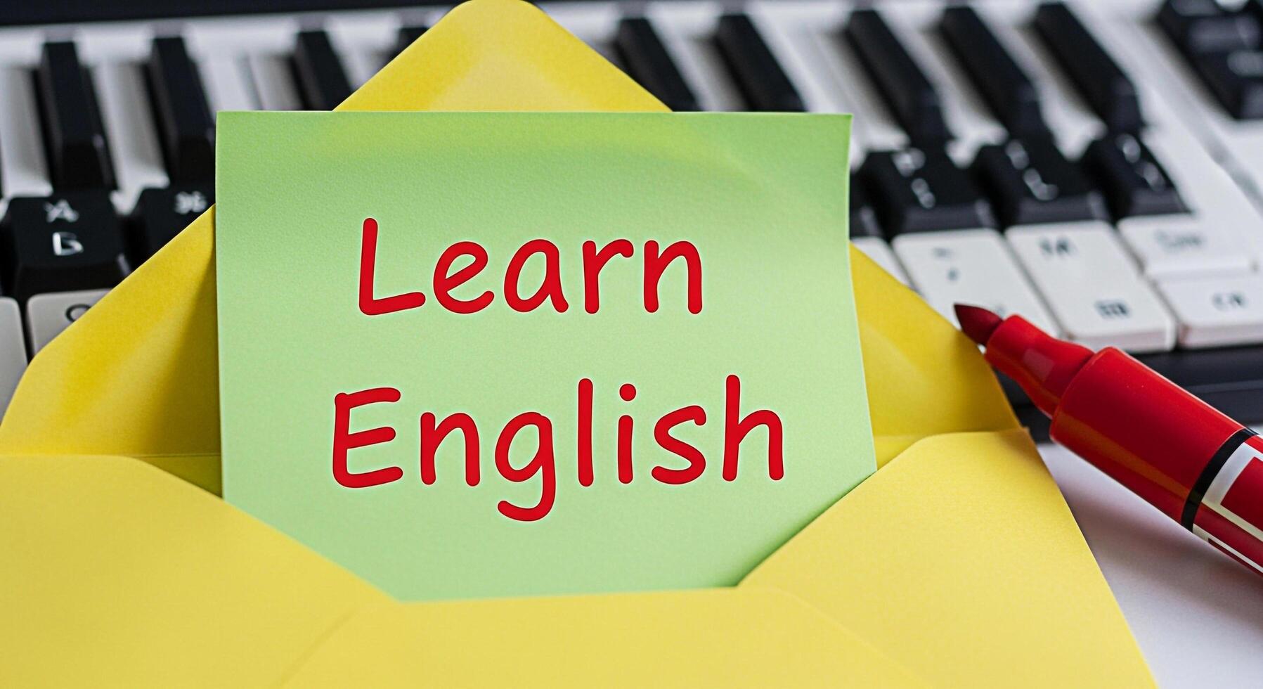 Bright green sticky note displaying Learn English in a yellow envelope against a piano keyboard suggesting language acquisition and musical creativity in an educational environment photo