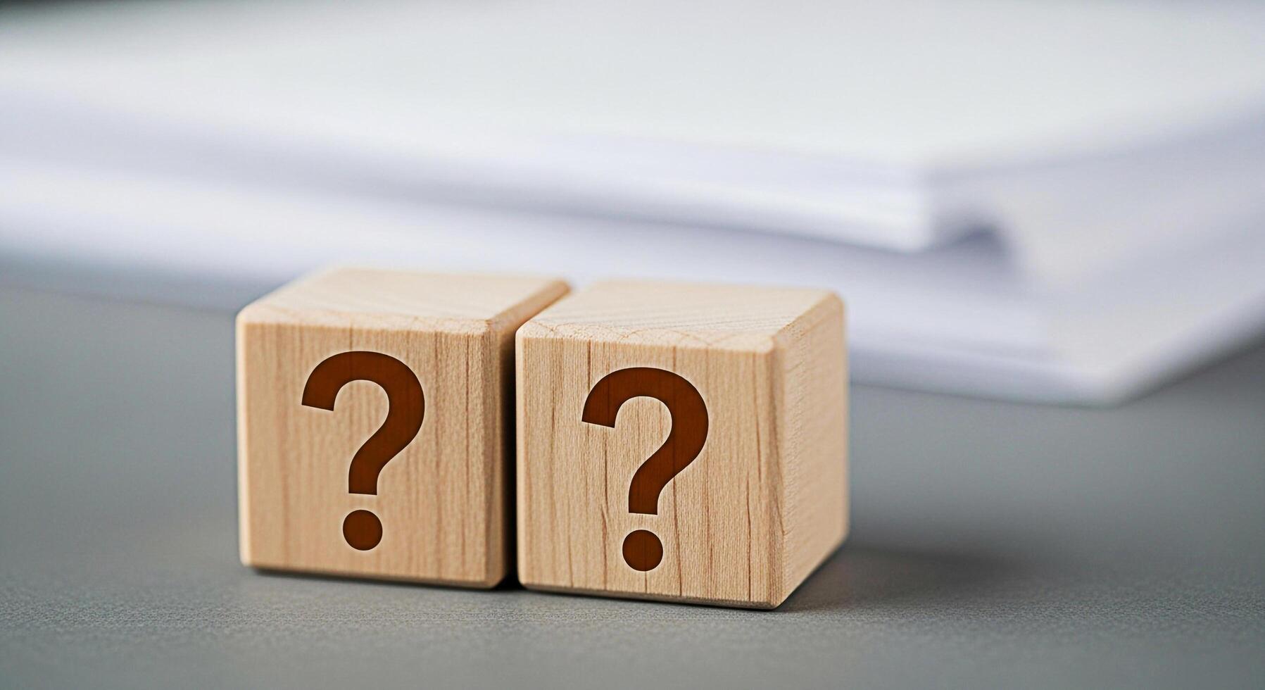 Two wooden blocks displaying question marks on a gray surface symbolizing uncertainty and the need for answers in a business or educational setting fostering curiosity and problemsolving photo