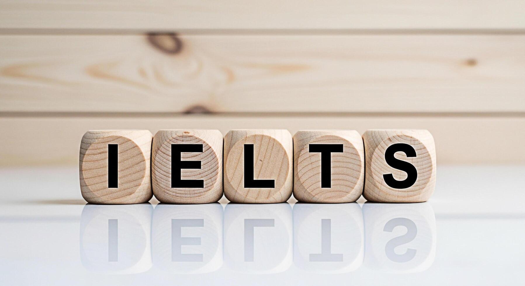 Wooden blocks spelling IELTS on a reflective surface against a light wood background representing the International English Language Testing System and the concept of language proficiency testing photo