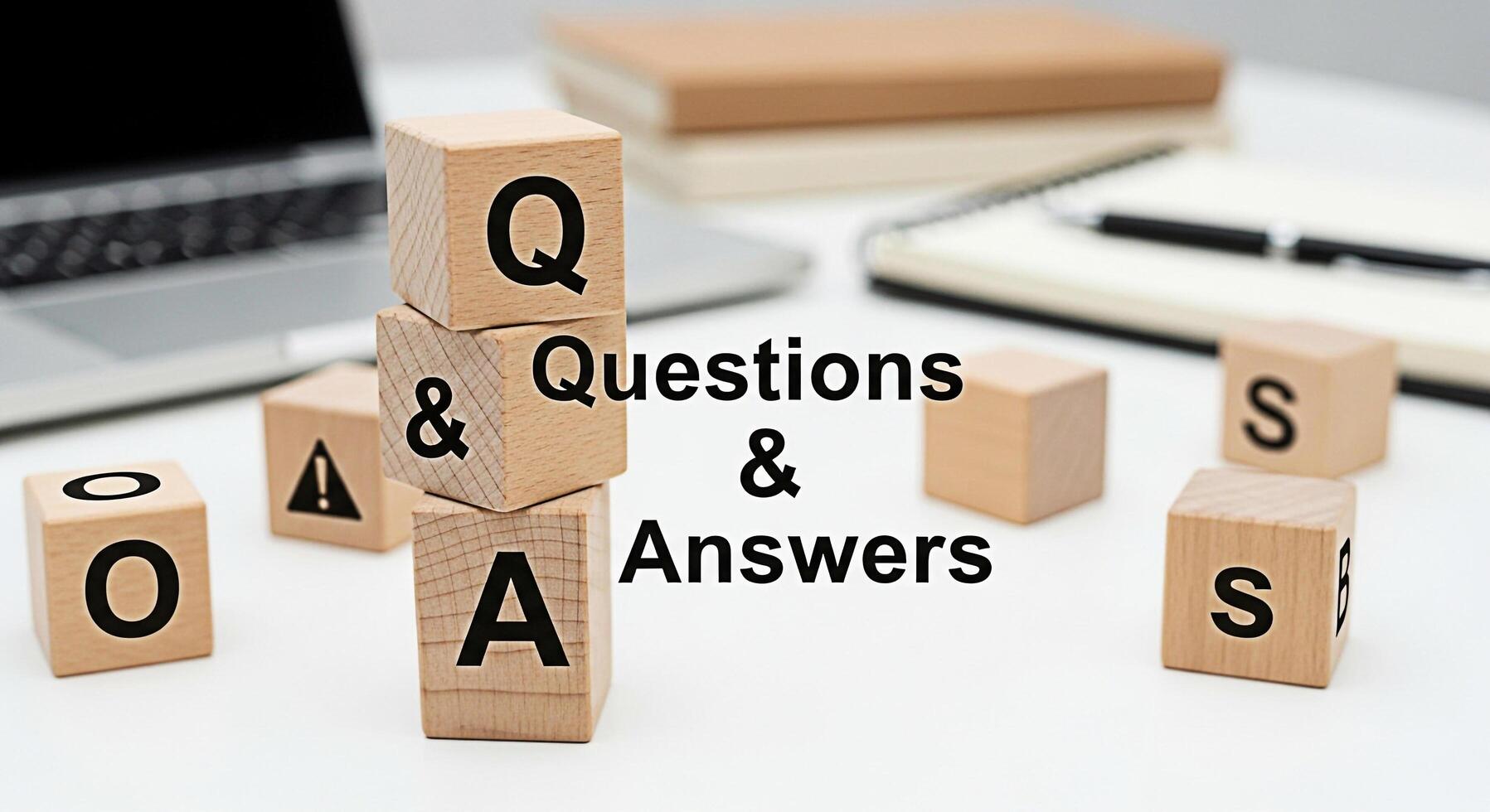 Wooden blocks displaying Questions Answers on a white desk with a laptop and notebook symbolizing information learning and problemsolving in a modern office environment fostering curiosity and knowled photo