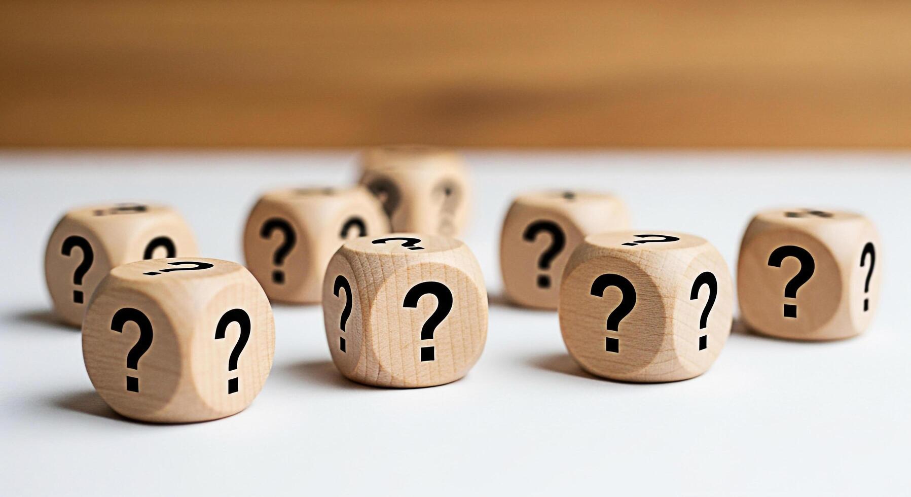 Wooden dice displaying question marks scattered on a white surface creating a sense of uncertainty and curiosity about the unknown inviting exploration and problemsolving in a bright studio setting photo