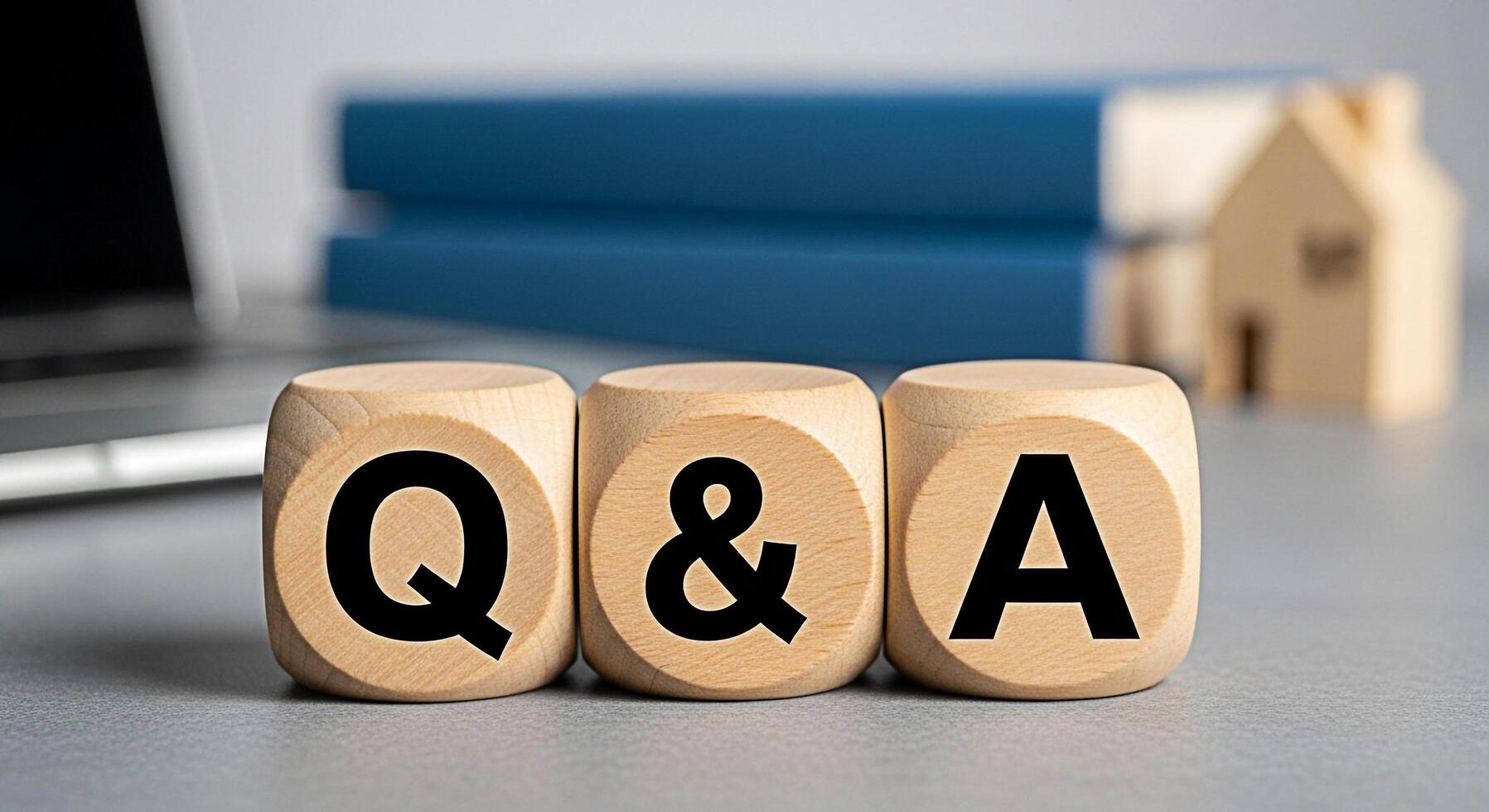 Wooden blocks displaying QA on a desk with a laptop and books representing information and knowledge encouraging questions and answers in a learning or business environment fostering curiosity photo