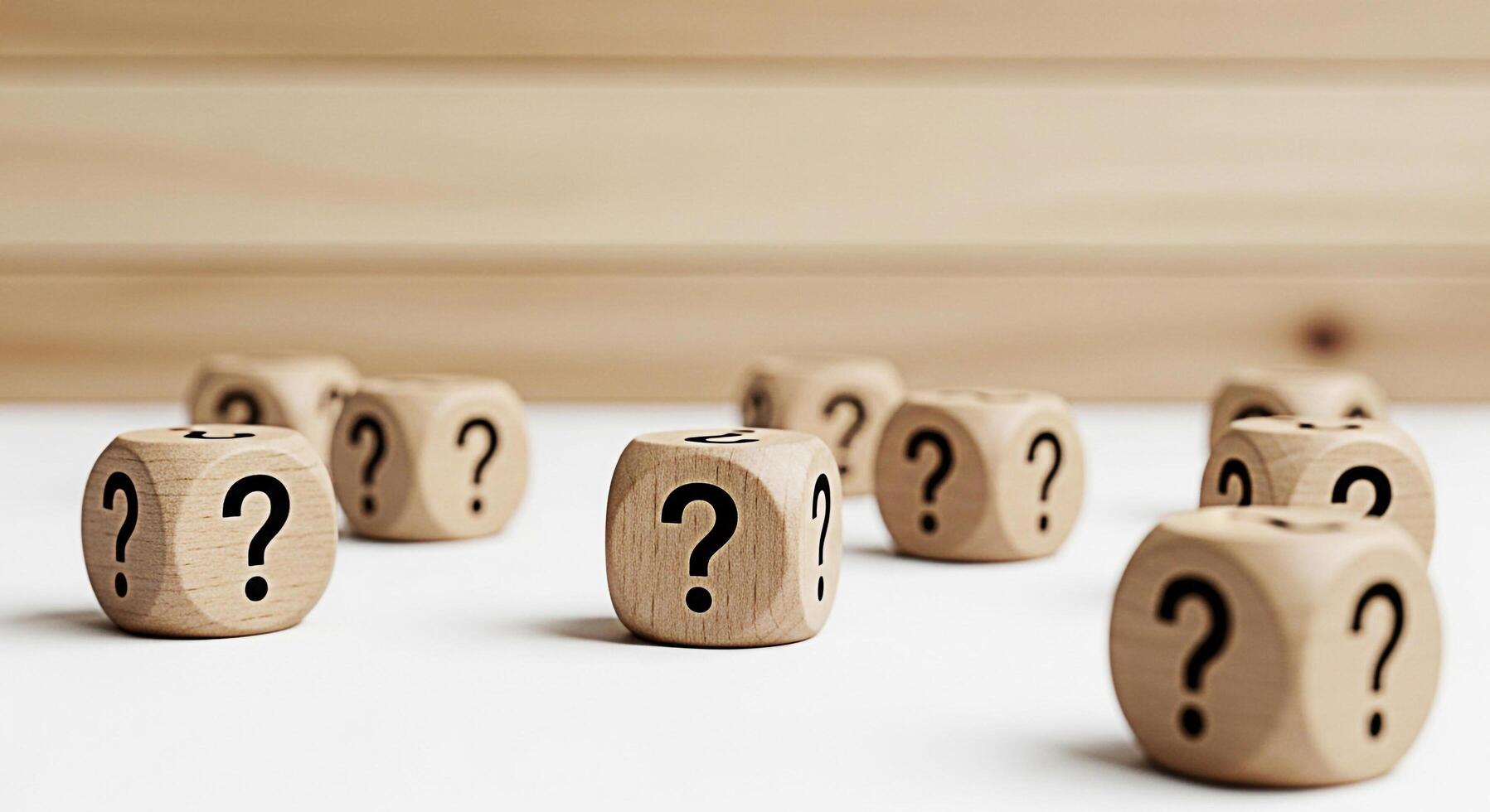 Wooden dice displaying question marks scattered on a white surface against a wood panel background symbolizing uncertainty inquiry and the search for answers in a bright and minimalist setting photo