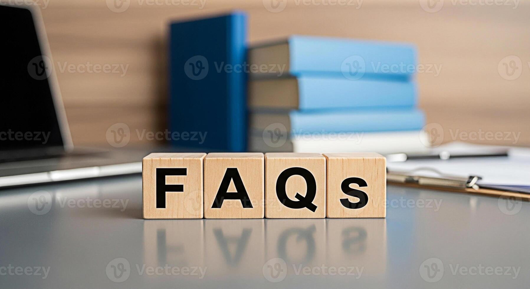 Wooden blocks spelling FAQs on a desk with a laptop and books representing information and support in a professional setting conveying a sense of clarity and helpfulness for customer service photo