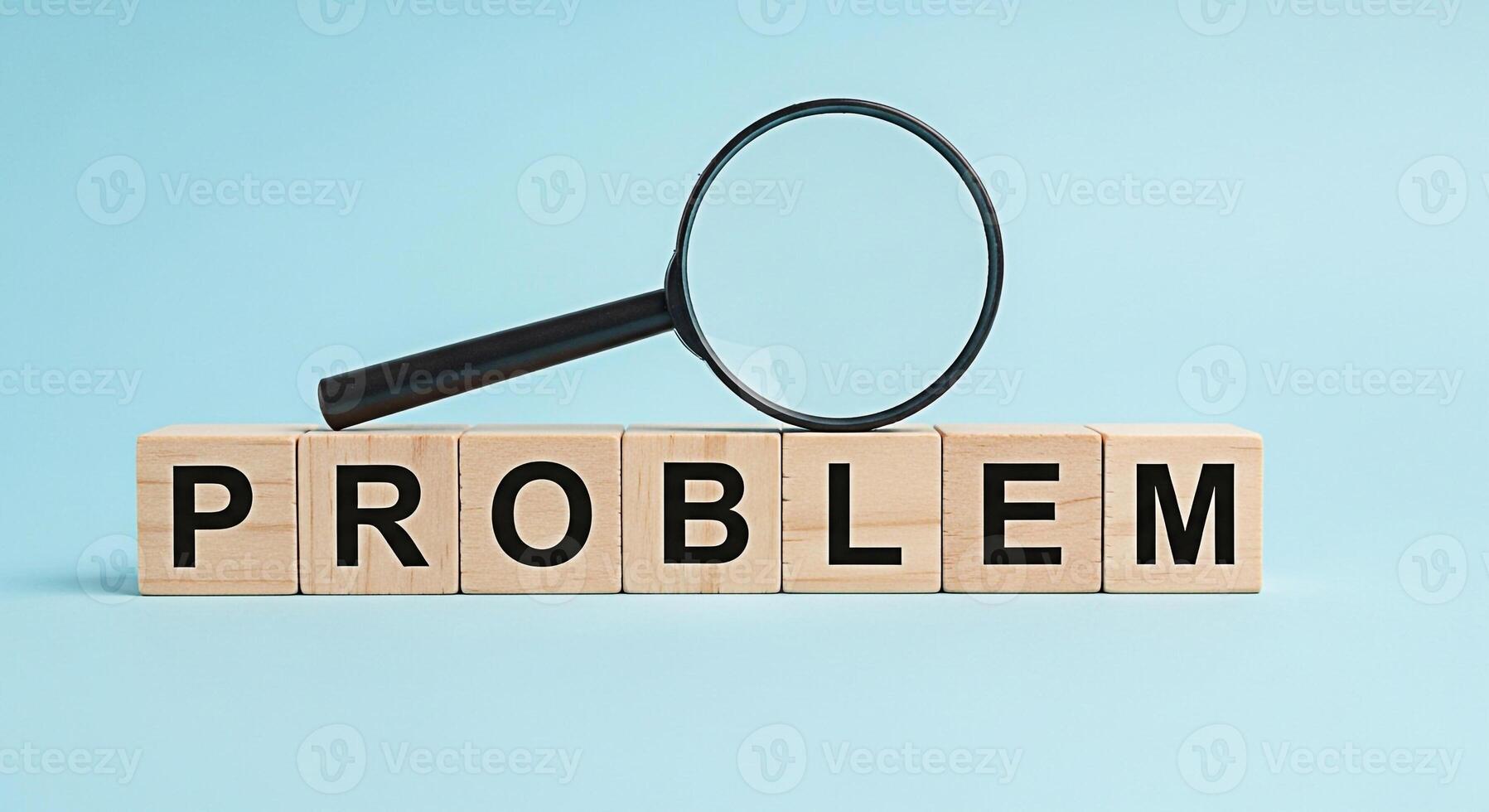 Magnifying glass examining the word PROBLEM spelled out with wooden blocks against a light blue background symbolizing analysis investigation and the search for solutions to complex issues photo