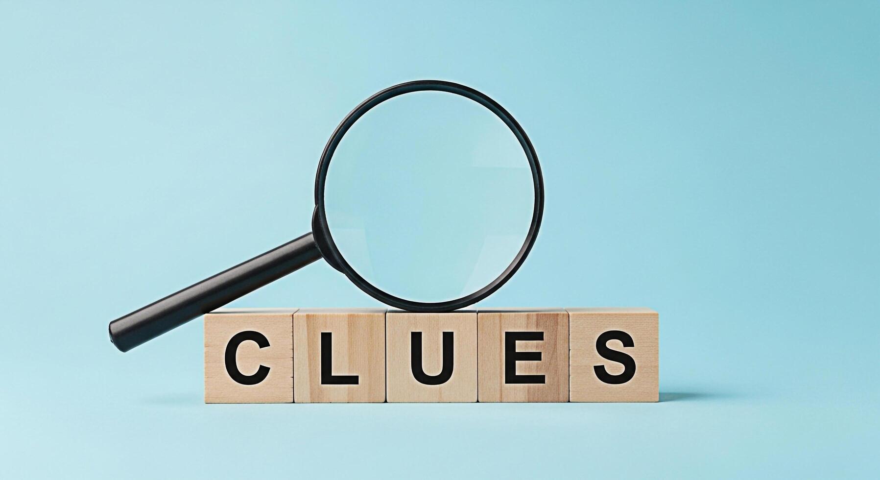 Magnifying glass hovering over wooden blocks spelling CLUES against a light blue background symbolizing investigation problemsolving and the search for answers in a clean and minimalist setting photo