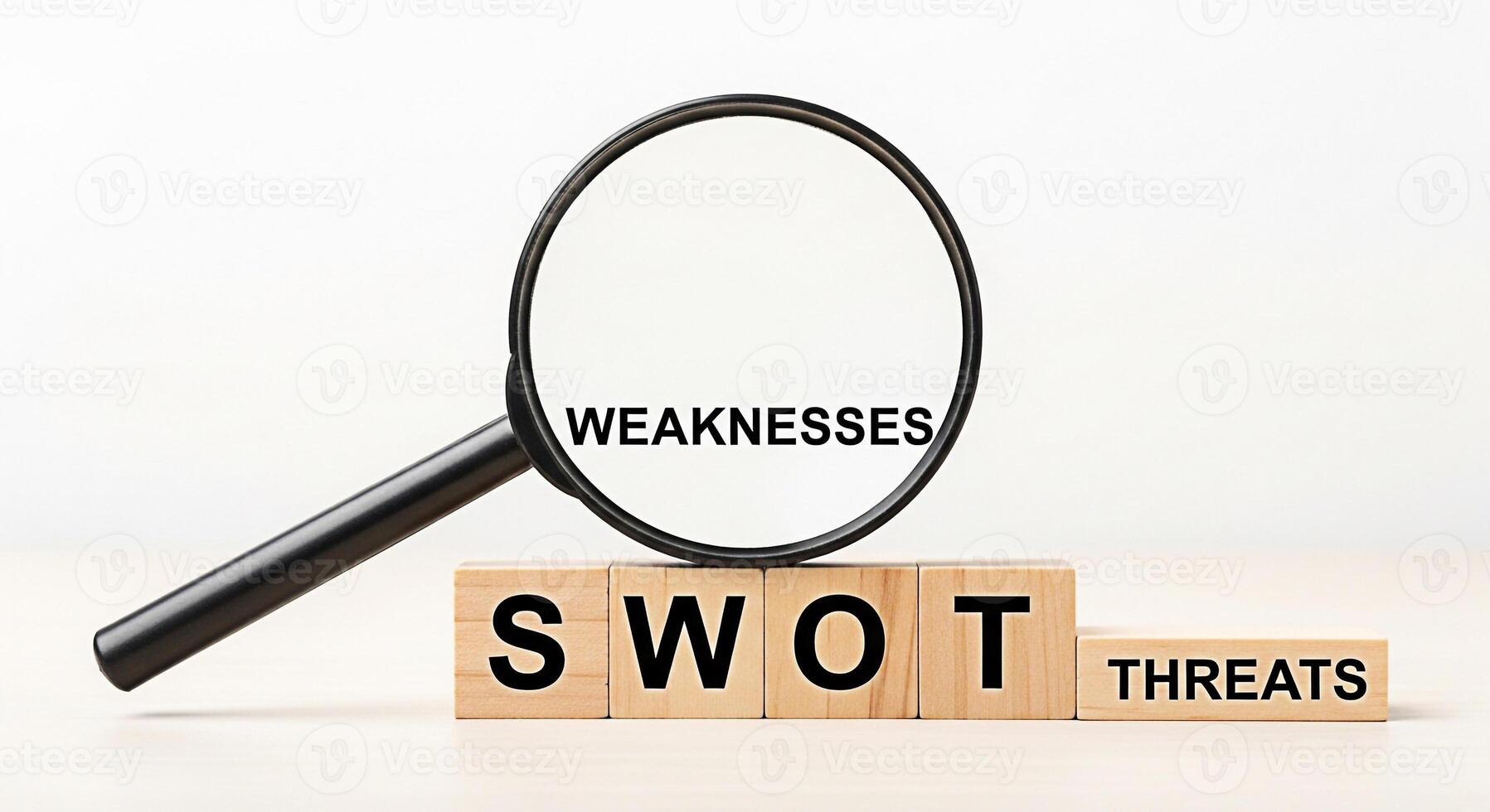 Magnifying glass examining Weaknesses in a SWOT analysis on wooden blocks revealing business vulnerabilities and strategic planning challenges in a bright analytical environment emphasizing risk asses photo