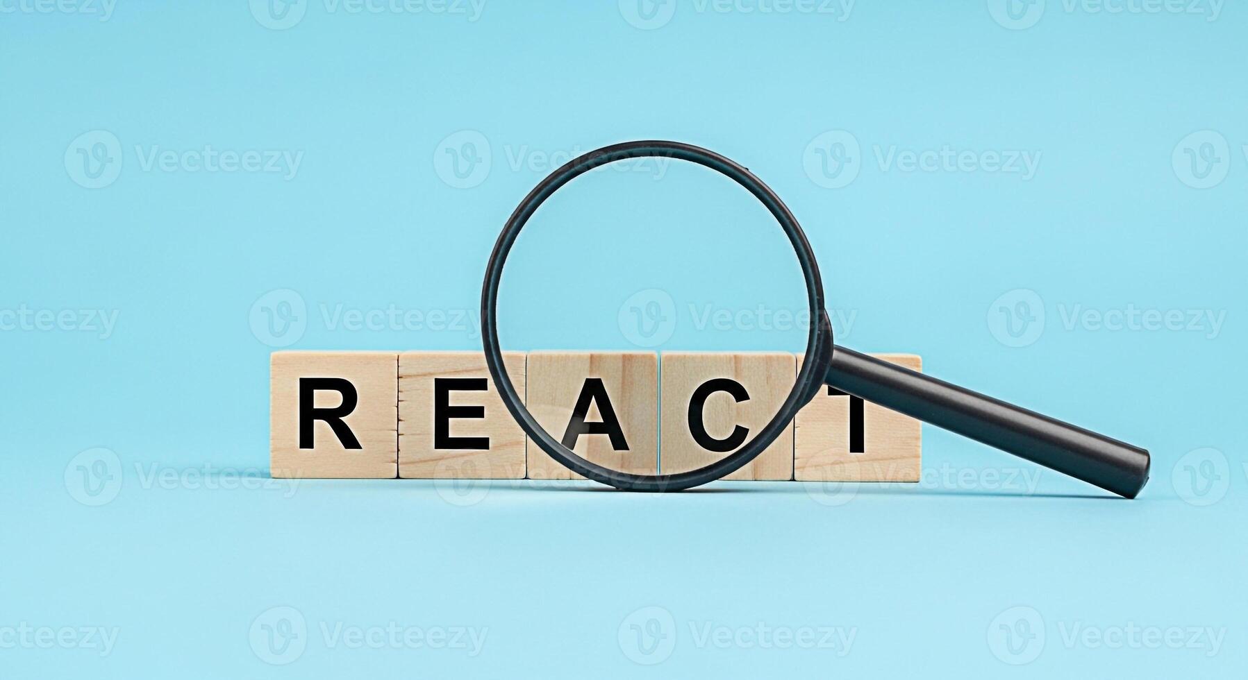 Magnifying glass inspecting wooden blocks spelling REACT on a light blue background symbolizing careful examination and analysis in the context of software development and frontend technologies photo
