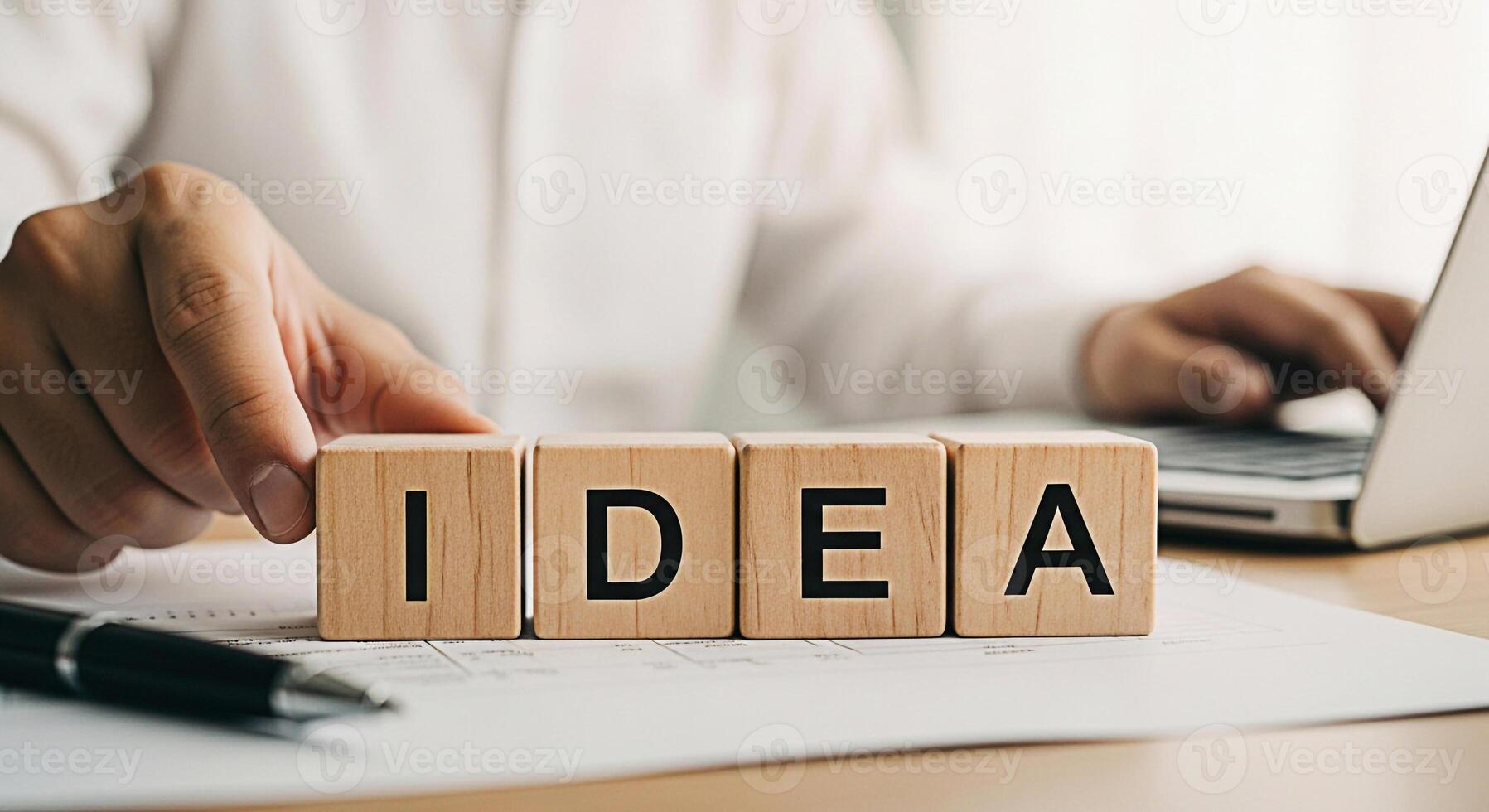 Focused professional arranging wooden blocks spelling IDEA on a desk brainstorming in a bright office setting symbolizing creativity and innovative thinking for business success and problemsolving photo