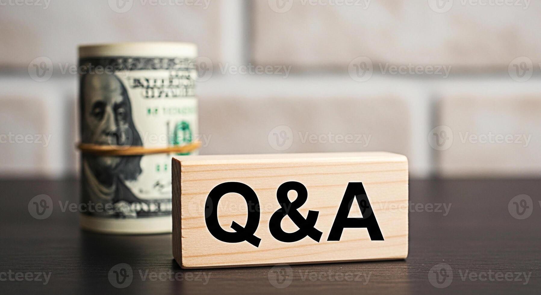 Roll of US currency and a wooden block with QA on a dark table against a brick wall symbolizing financial questions and answers investment advice and economic discussions in a professional setting photo