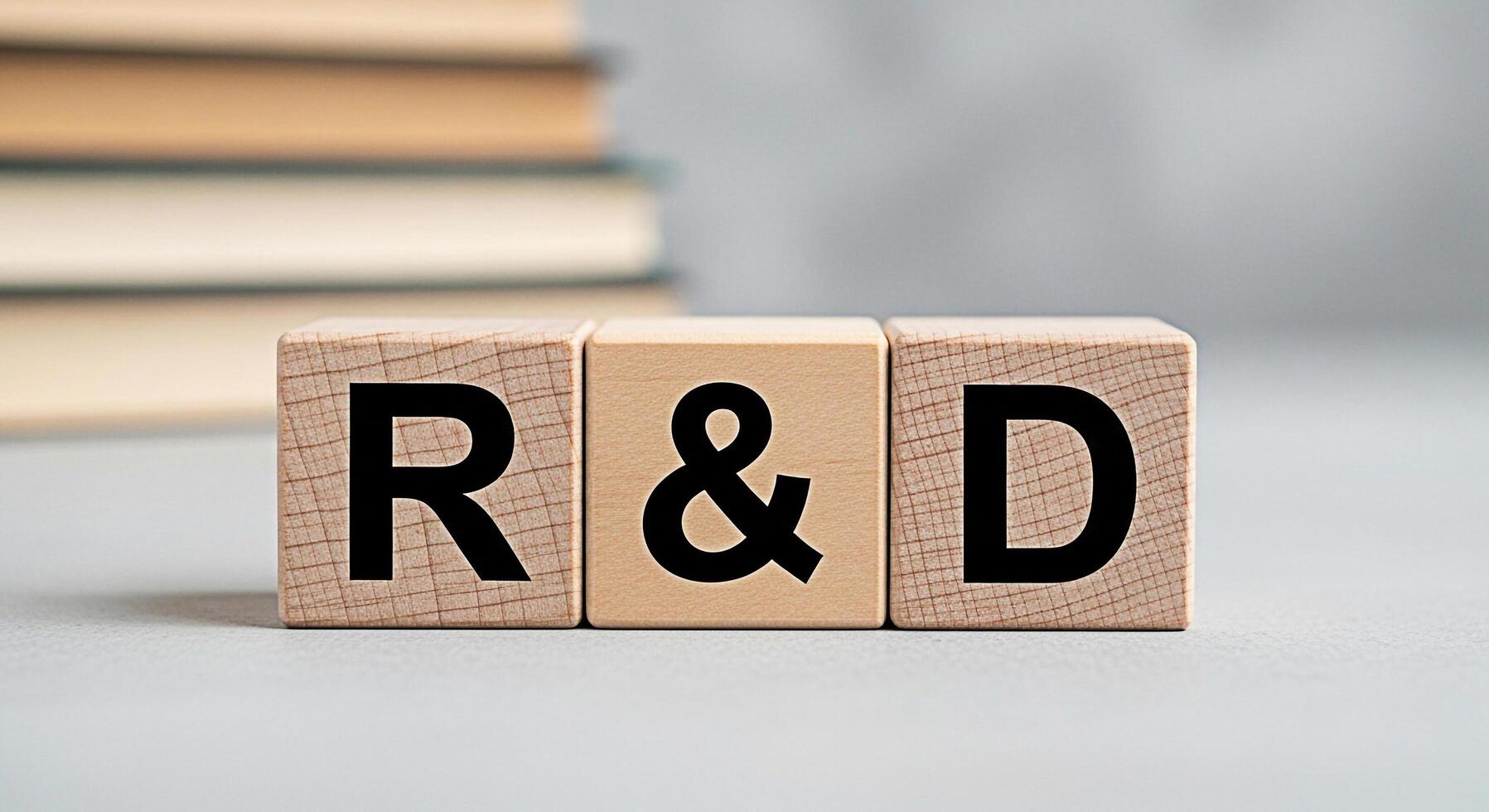 Wooden blocks displaying RD on a neutral surface with a stack of books in the background representing research and development in a simple and conceptual way photo