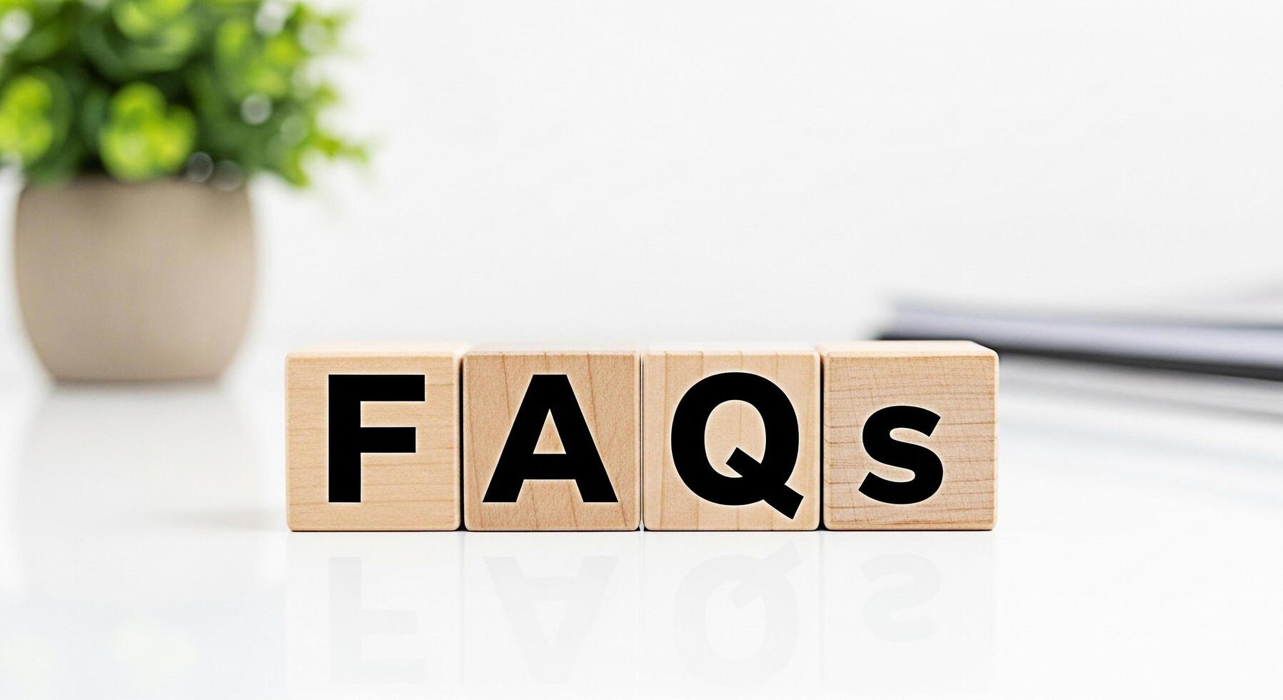 Wooden blocks spelling FAQs on a white table with a plant in the background representing frequently asked questions and providing information and support in a clean and professional environment photo