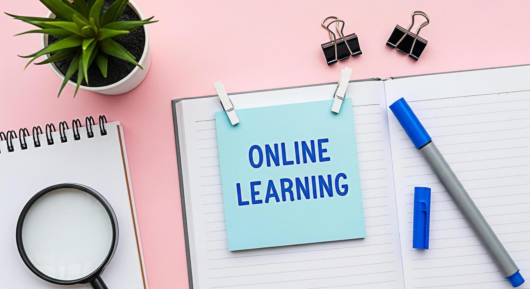 Overhead shot of a notebook displaying an online learning message on a sticky note in a bright pink workspace conveying a modern and accessible educational concept photo