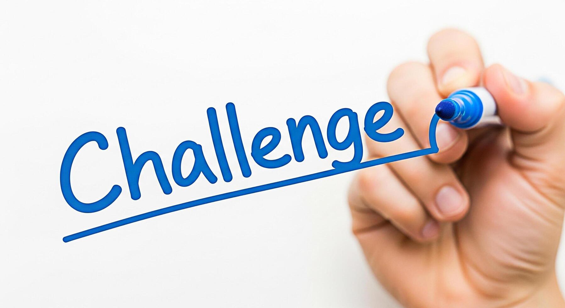 Hand underlining the word Challenge in blue marker on a white background symbolizing overcoming obstacles and achieving success through determination and perseverance in a competitive environment photo