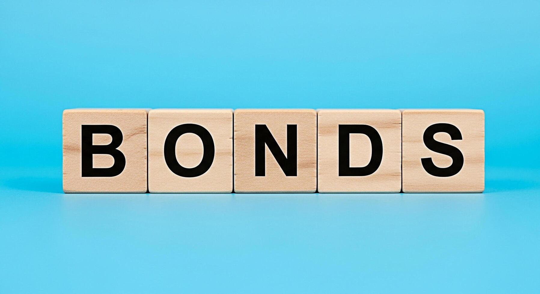 Wooden blocks spelling BONDS on a blue background representing financial investments and security emphasizing stability and longterm growth in a simple and clean studio setting photo