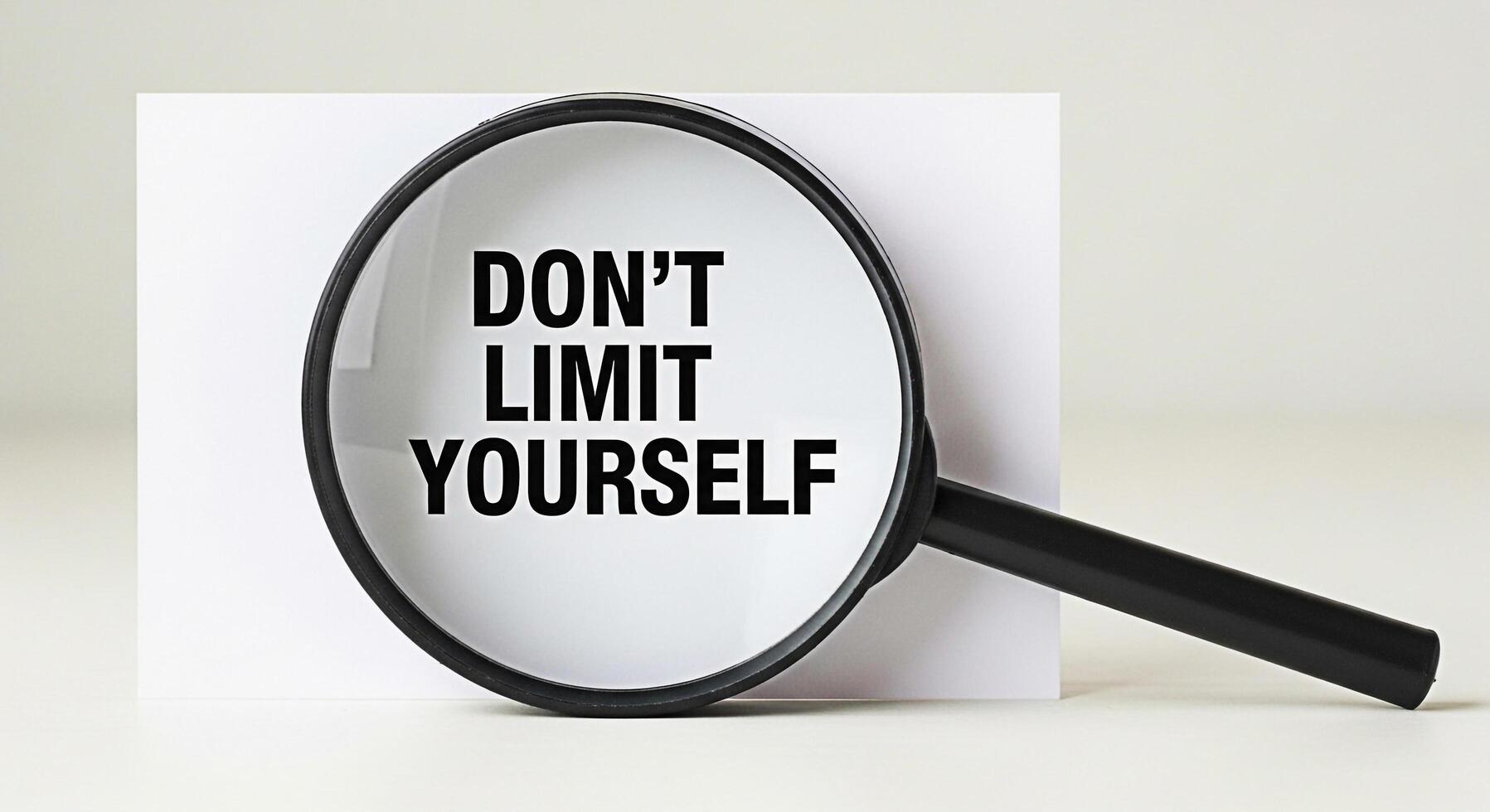 Magnifying glass revealing the message Dont Limit Yourself on a white card in a bright studio setting symbolizing selfimprovement motivation and the power of positive thinking photo