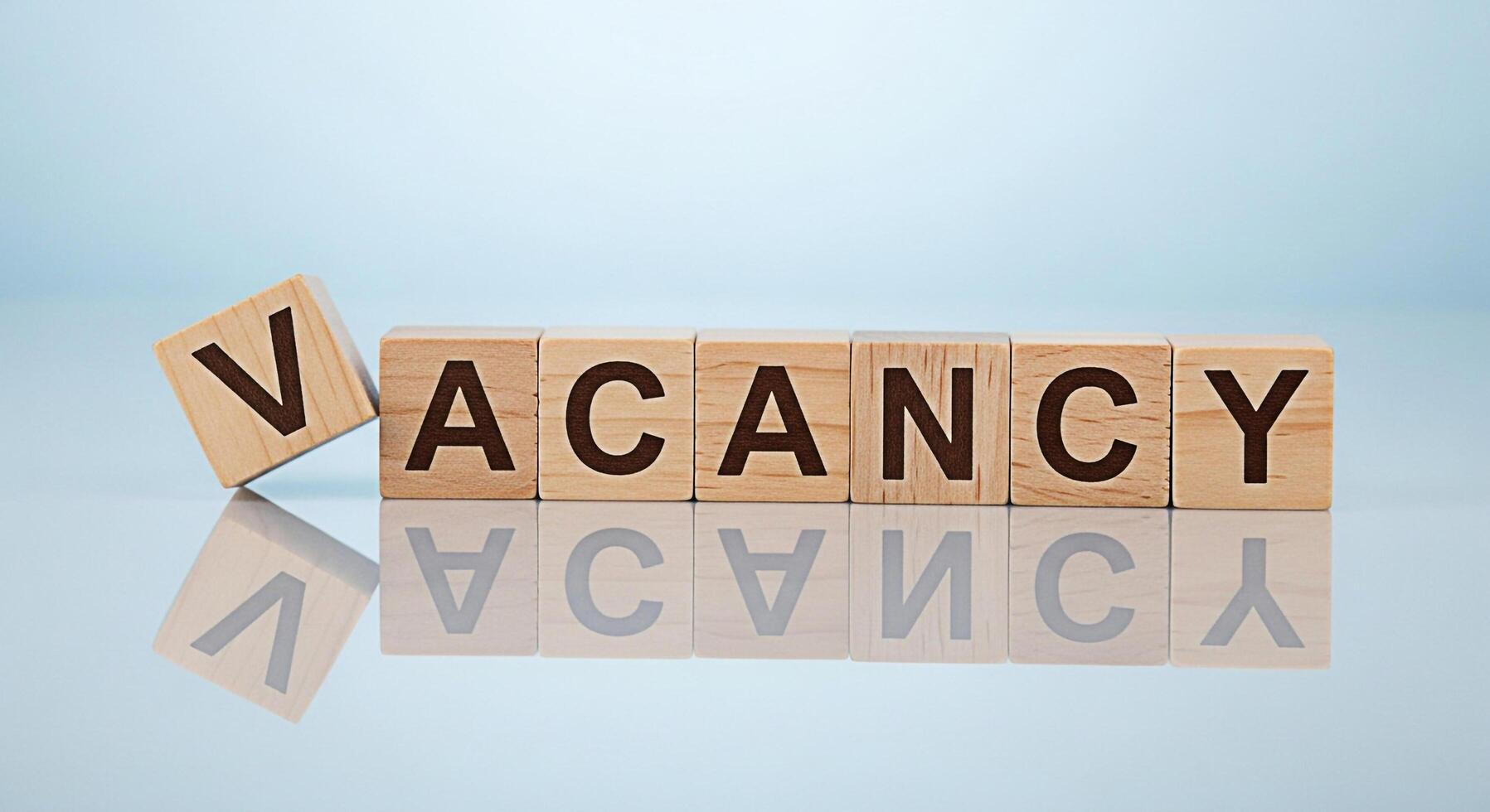 Wooden blocks spelling Vacancy on a reflective surface symbolizing job openings and career opportunities in a competitive job market creating a sense of urgency and potential for growth photo