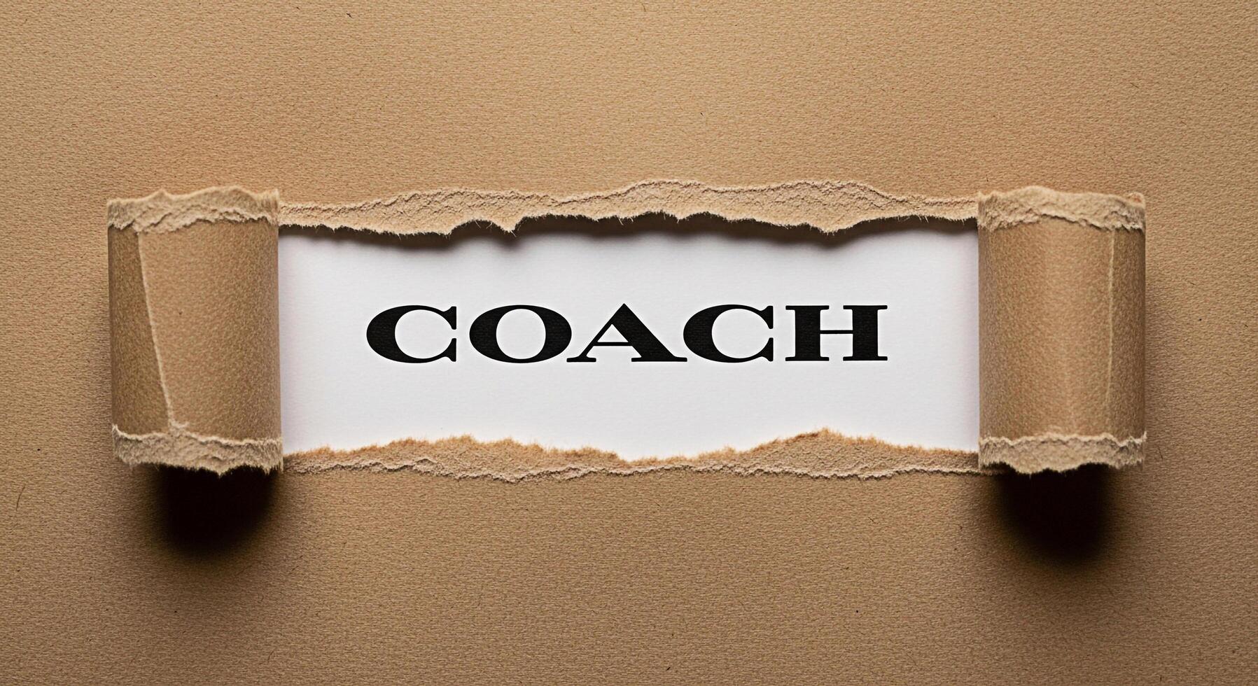 The word COACH revealed through a torn brown paper background symbolizing guidance and support creating a sense of discovery and unveiling potential with a motivational and empowering mood photo