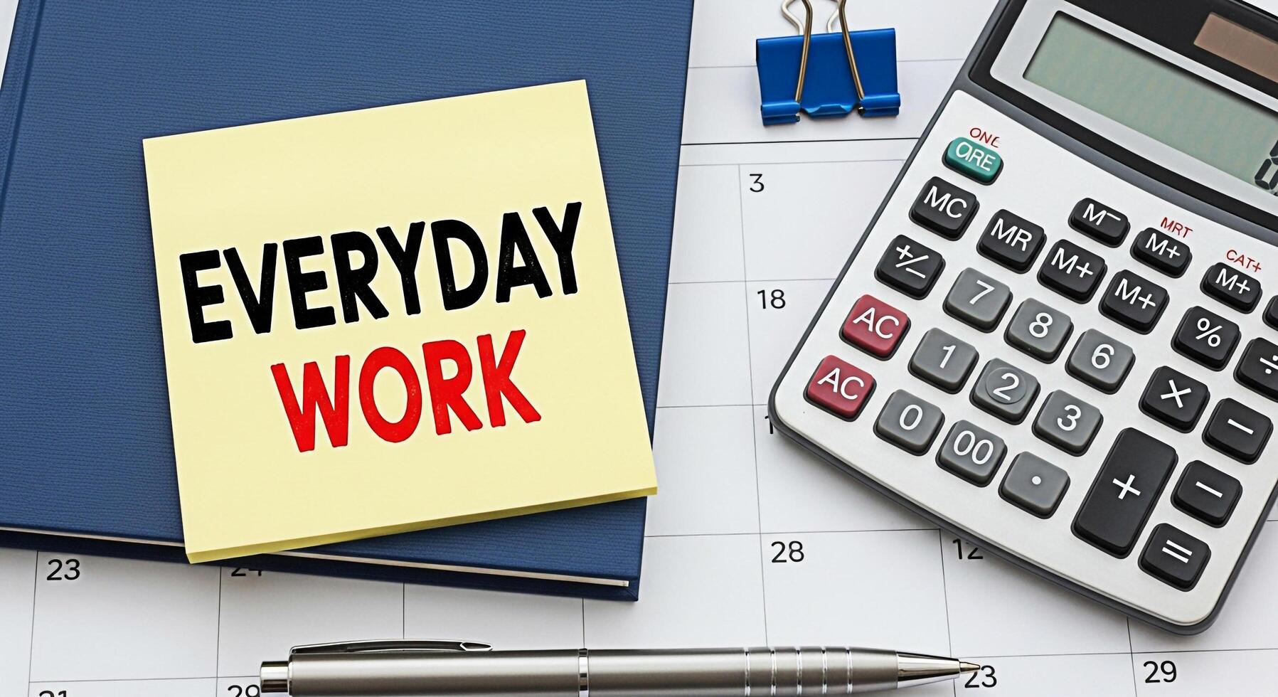 Closeup of a desk with a notepad displaying Everyday Work on top of a planner alongside a calculator and pen symbolizing routine tasks and daily office life in a structured environment photo