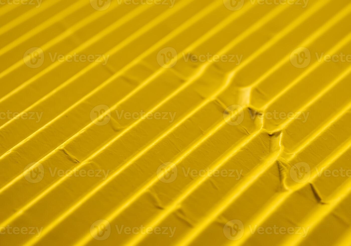 Close-up of a vibrant golden yellow patterned surface showcasing rhythmic diagonal lines and textured grooves creating an interesting abstract photo