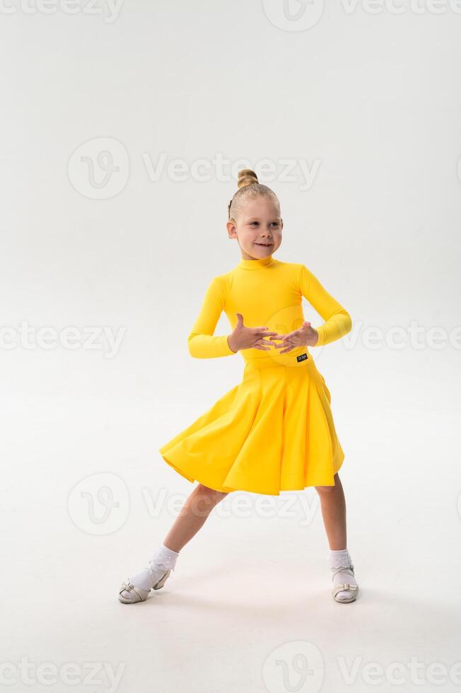 Child in bright yellow practicing choreography with hearing device. Confidence, concentration, and harmony of movement despite deafness, showing inclusion and technological progress in photo