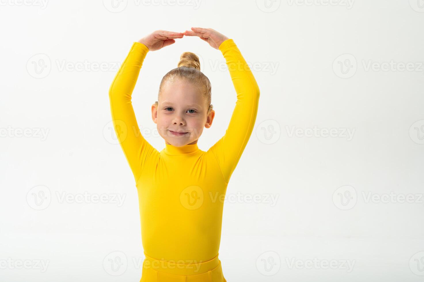 Smiling girl in bright yellow practicing choreography with hearing device. Confidence, concentration, and harmony of movement despite deafness, showing inclusion and technological progress in photo