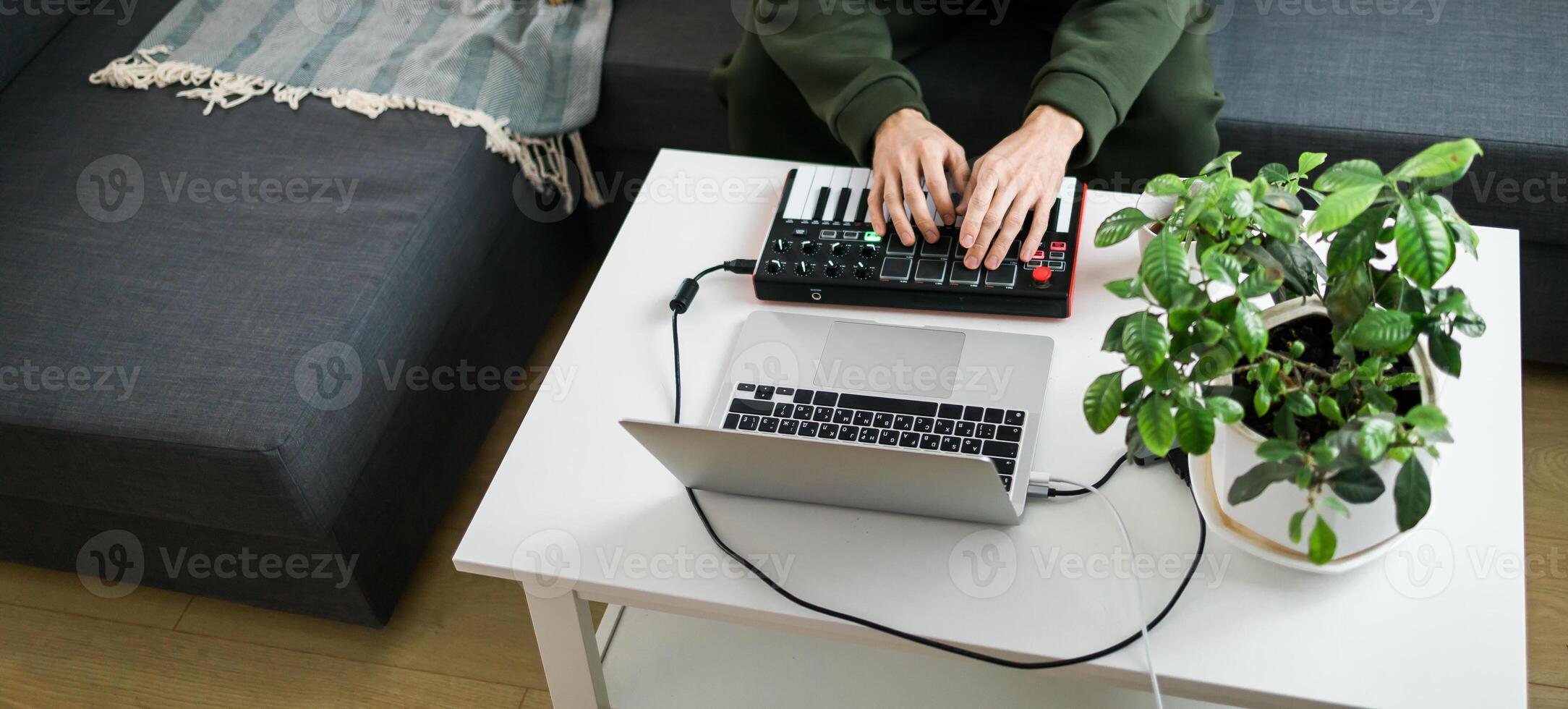 Top view guy recording electronic music track with portable midi keyboard on laptop computer in home studio. Producing and mixing music beat making and arranging audio photo