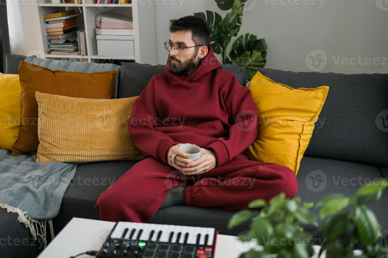 Guy recording electronic music track with portable midi keyboard on laptop computer in home studio. Producing and mixing music beat making and arranging audio content with professional audio devices photo