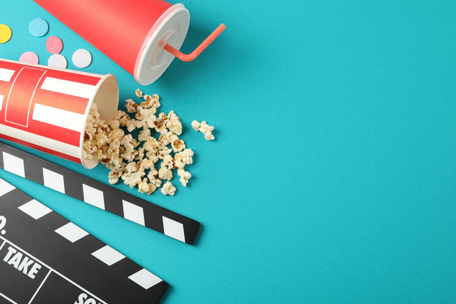 Flat lay. Drink, bucket with popcorn, clapperboard and confetti on color background, copy space photo