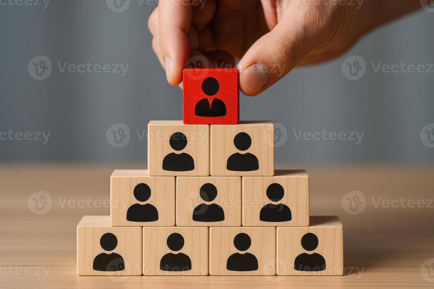 Leadership team management concept with wooden blocks stacked in pyramid shape and hand placing red block on top symbolizing leadership and team management success photo
