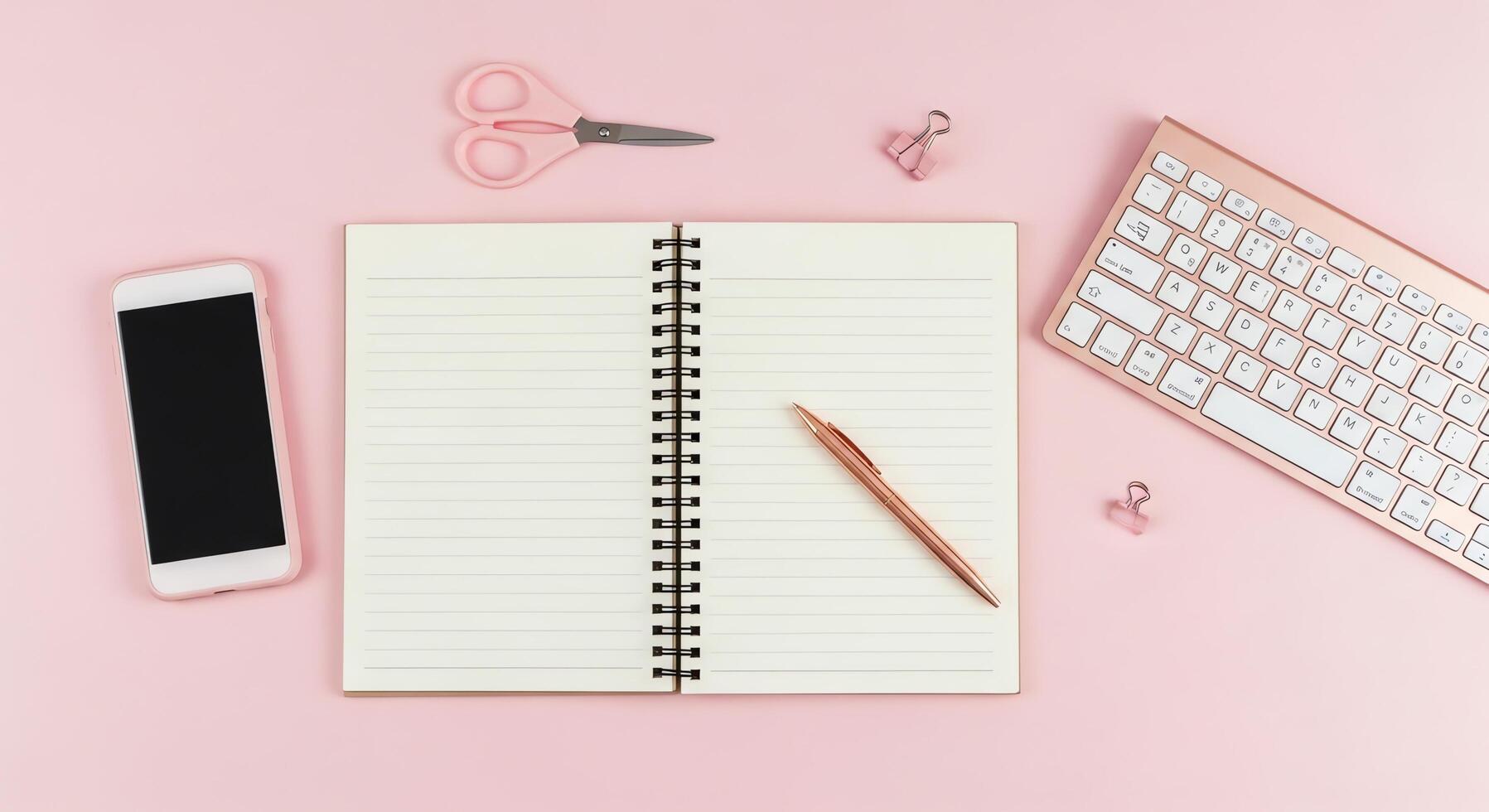 Flat lay of a modern workspace with a smartphone, keyboard, notebook, and scissors on a pink background photo