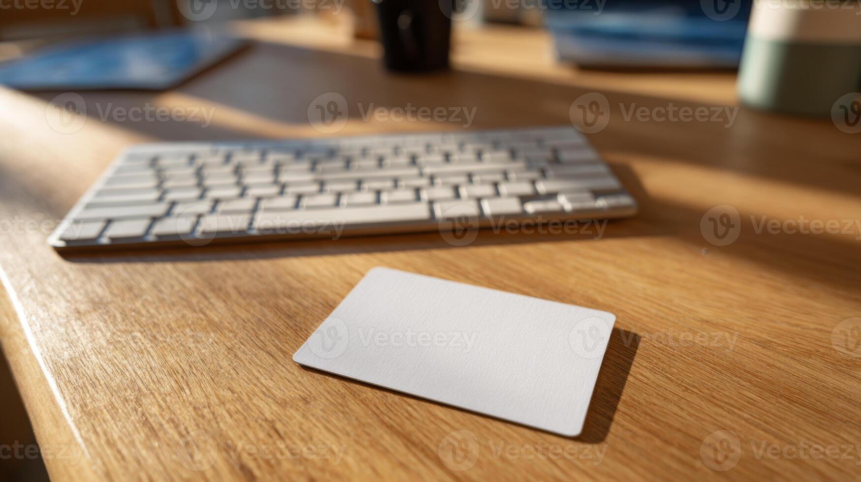 A clean workspace featuring a blank card on a wooden table beside a keyboard, evoking creativity and organization. photo