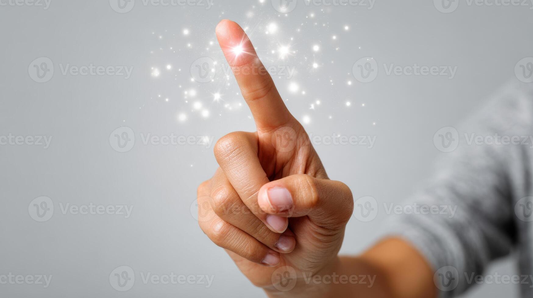 A close-up of a hand with a delicate touch, creating a sparkling effect, evoking magic and wonder in a light gray setting. photo