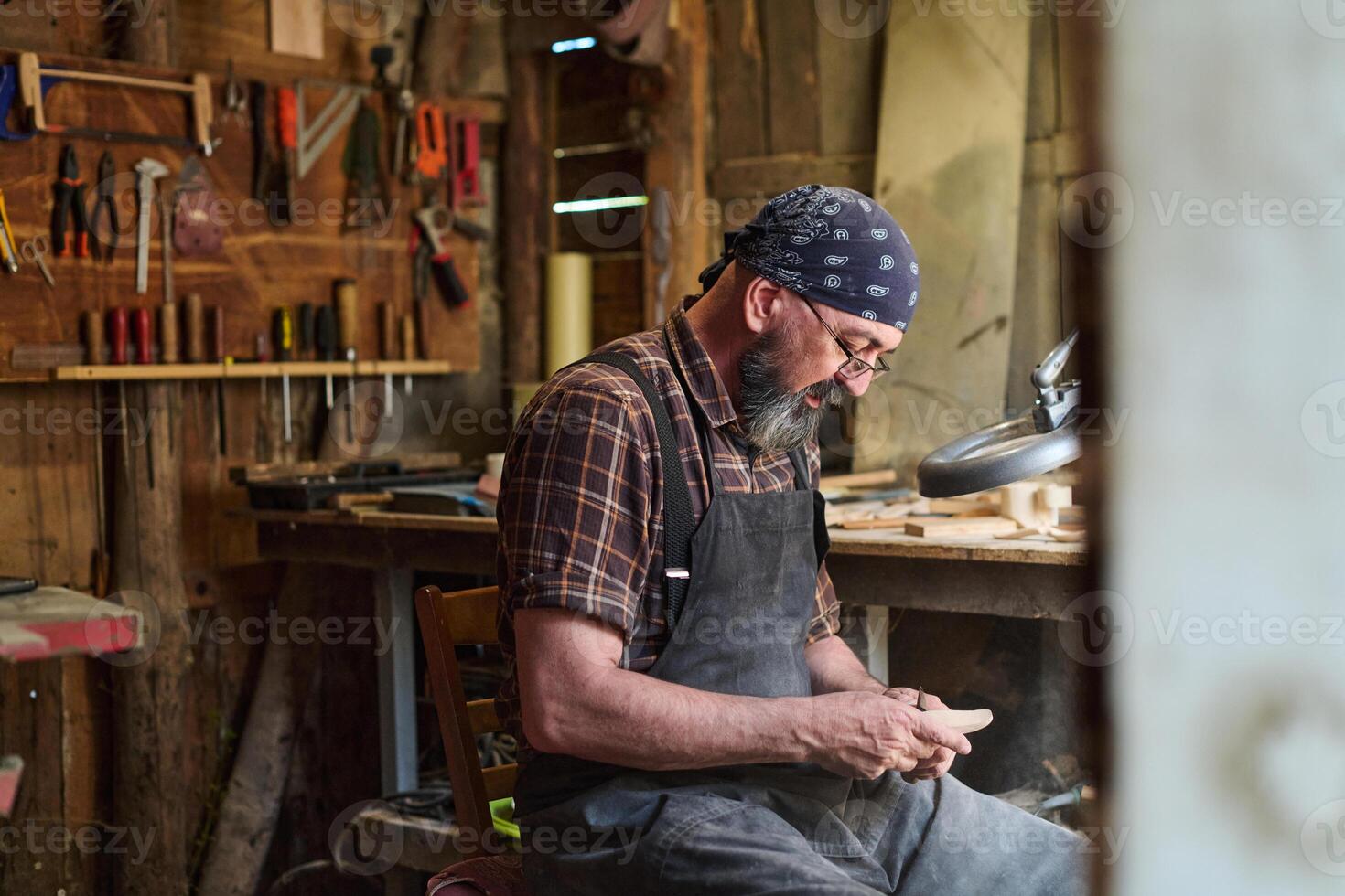 Craftsman working in his workshop, artisan shaping wood with hand tools, woodworking project, small business owner, hobbyist in rustic setting, creative process, skilled labor. photo