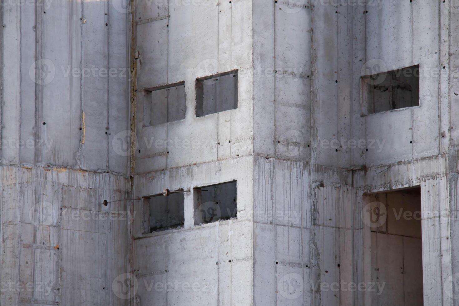 Exterior of Concrete Wall Frame of Building under Construction. Architectural origin of Structure. Monolithic box with holes for windows and floor slabs on sunny day at Construction Site. photo