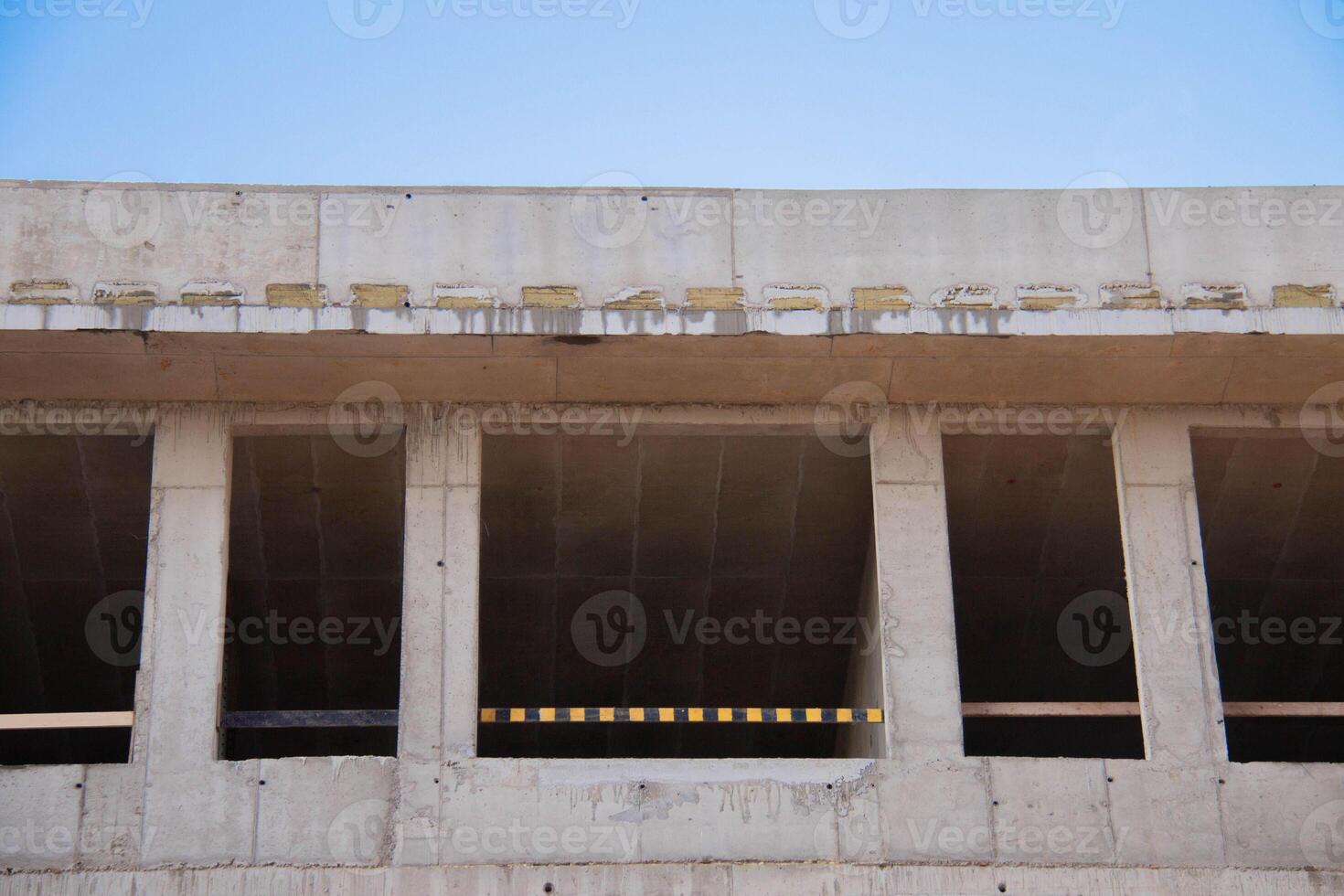 Front view Concrete Wall Frame of Building under Construction. Formwork Prints with Thermal Pads, black-yellow Fence. Monolithic box window holes Construction Site. Architectural origin Structure. photo