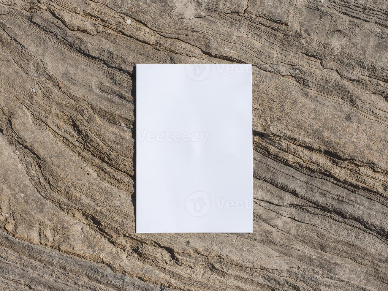 Blank vertical paper mockup on a rough rock texture. Empty A4 or A5 card on a natural stone background. photo