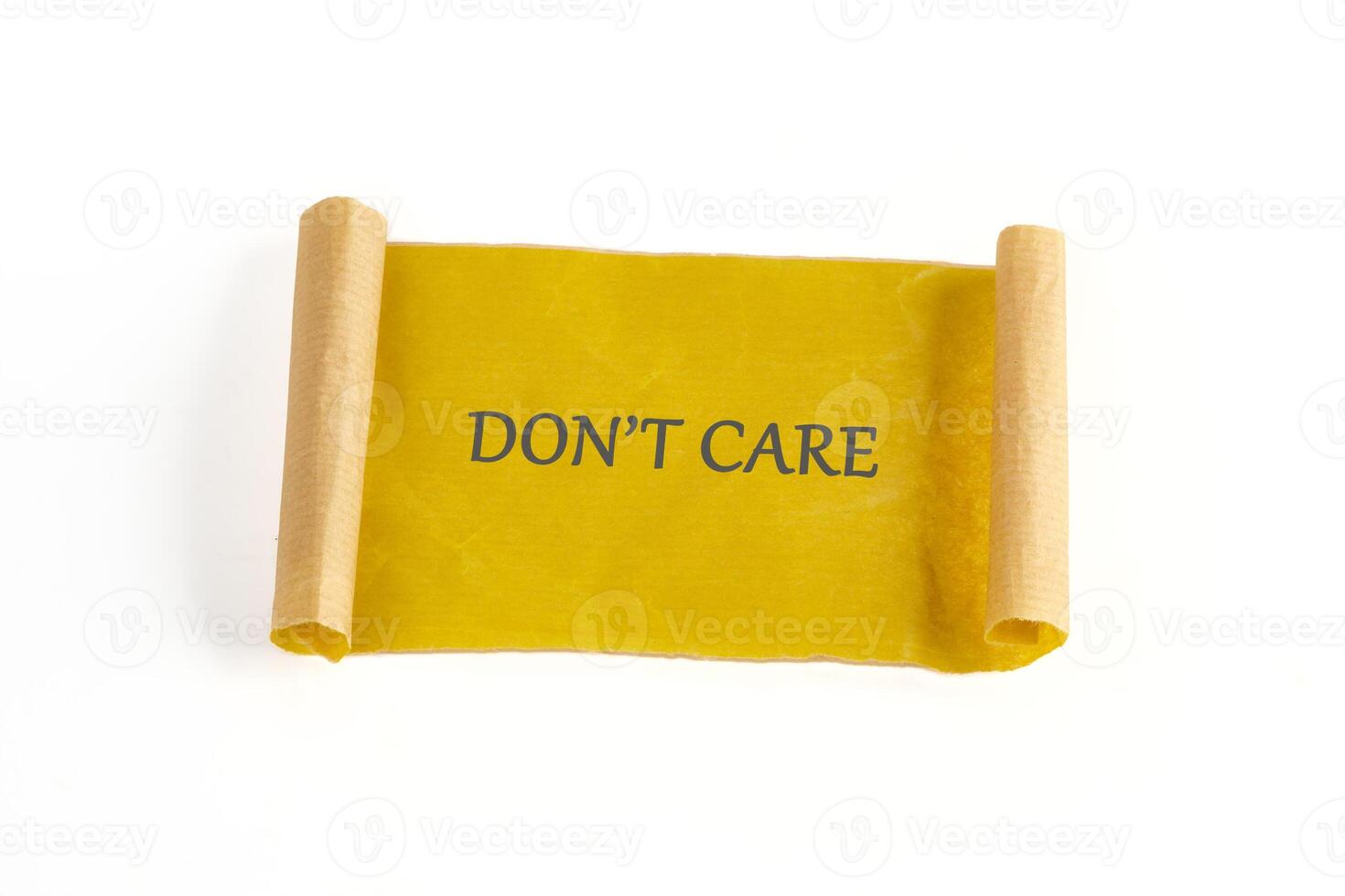 A yellow scroll displays a message in gray letters. It reads DONT CARE and rests on a white background. The scroll is rolled at both ends in a light brown color photo